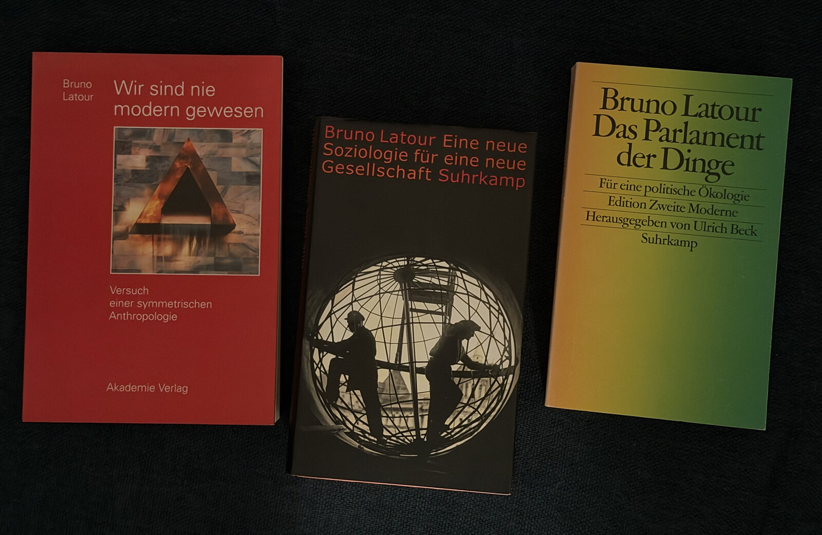 Drei Latour-Bände auf dunklem Stoff – „Wir sind nie modern gewesen“, „Eine neue Soziologie für eine neue Gesellschaft“ und „Das Parlament der Dinge“